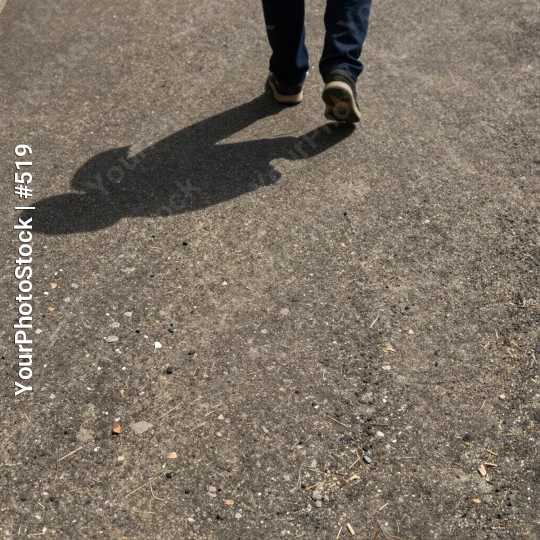 Person Walking on Wet Concrete Pavement shadow