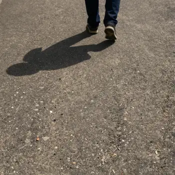 Person Walking on Wet Concrete Pavement shadow