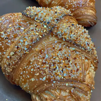Freshly Baked Croissant with Colorful Sprinkles on Grey Plate