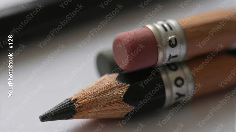 Two Pencils with Erasers Resting on Desk blurred background