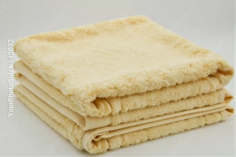 Neatly Folded Towels Stack light yellow tidy white background hotel