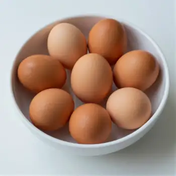 Six Brown Eggs in a White Bowl arranged scattered