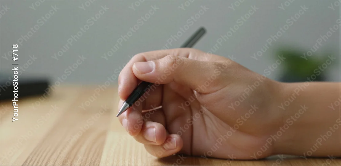 Hand Holding Black Stylus Pen on Wooden Surface