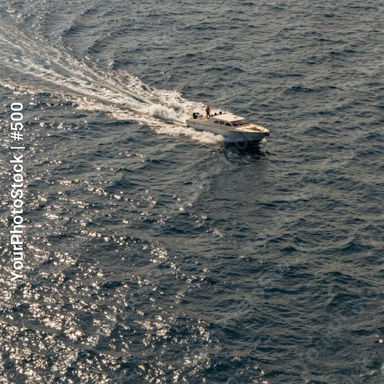 Fast-moving white boat on ocean with clear blue water and sunny skies