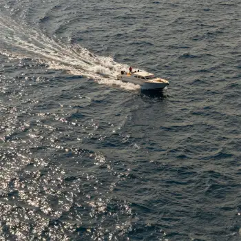 Fast-moving white boat on ocean with clear blue water and sunny skies