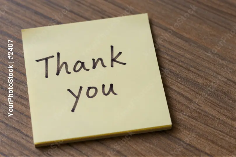 Close-up of 'Thank you' sticky note on wood cursive