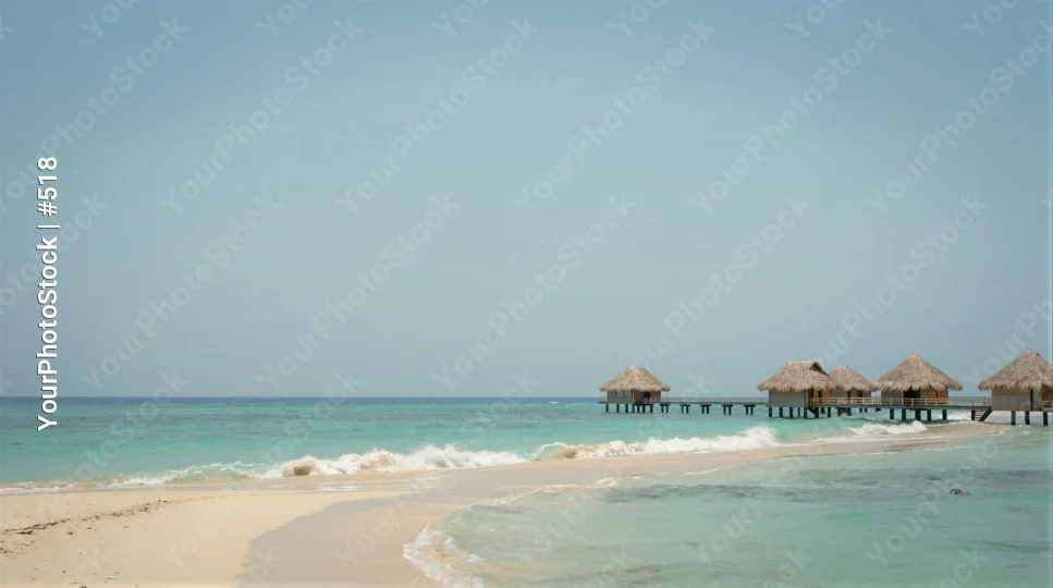 Peaceful Beach with Wooden Pier and Clear Blue Water