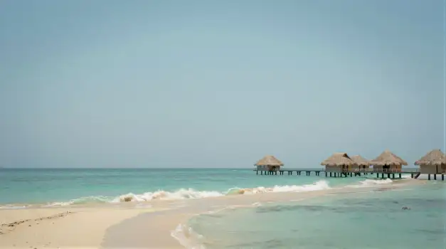 Peaceful Beach with Wooden Pier and Clear Blue Water