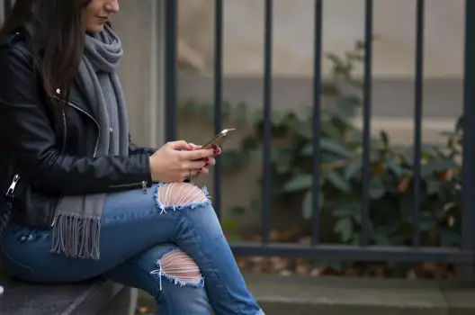 Young Woman Texting on Bench black leather jacket