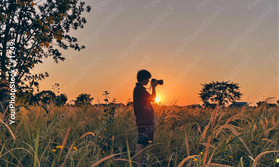 Person Taking Sunset Photo in Grass Field taking photo