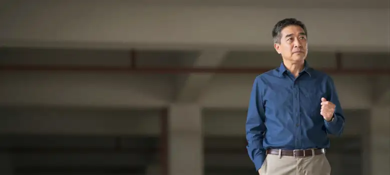 Middle-aged Asian man giving a presentation in an empty room business corporate