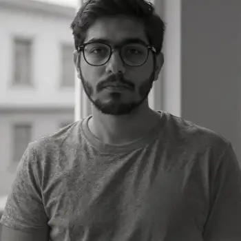 Young Man with Beard and Glasses Standing by Window black and white