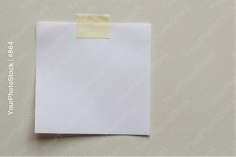 White Paper with Yellow Sticky Note Hanging on Beige Wall