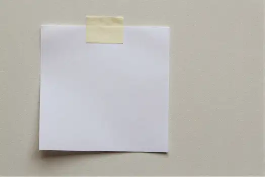 White Paper with Yellow Sticky Note Hanging on Beige Wall