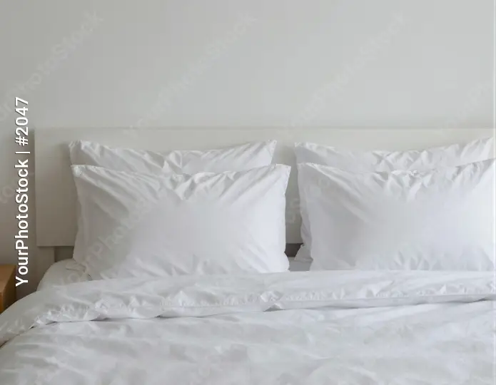 White Bed with Pillows in Minimalist Setting headboard hotel
