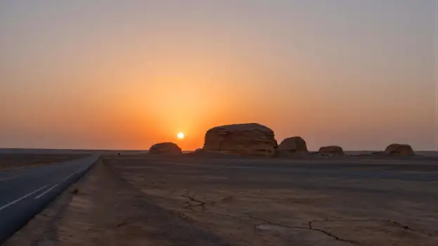 Vast Desert Landscape with Setting Sun and Rock Formations