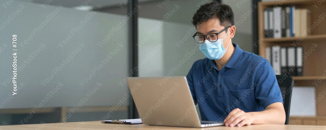 Young Man Working at Desk in Office laptop bookshelf