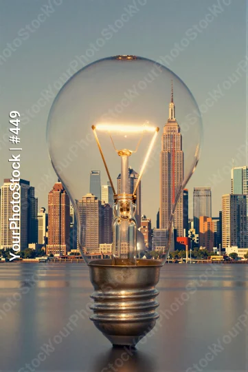Light Bulb on Reflective Surface Against City Skyline at Sunset