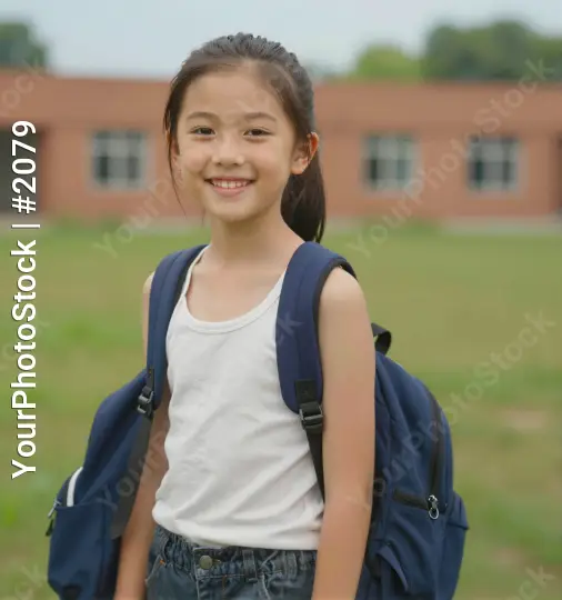Happy young girl standing in front of brick building student