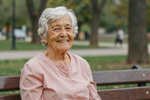 Elderly Woman Smiling on Wooden Bench in Park