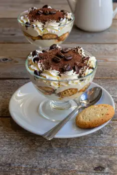Two Glass Trifles with Whipped Cream and Chocolate Shavings on Rustic dessert