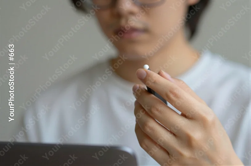 Close-up of Hand Holding Pen or Stylus Over Tablet