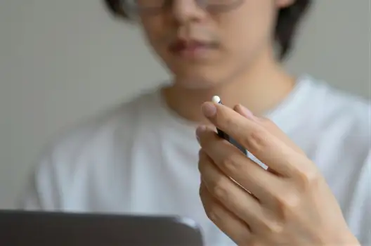 Close-up of Hand Holding Pen or Stylus Over Tablet