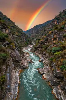 Serene River Flowing Through Rocky Gorge at Sunset