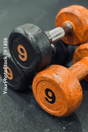 Old Black and Orange Dumbbells on Black Surface