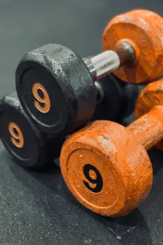 Old Black and Orange Dumbbells on Black Surface