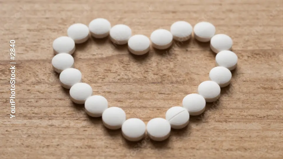 Heart-shapedwhite pills beads on a surface