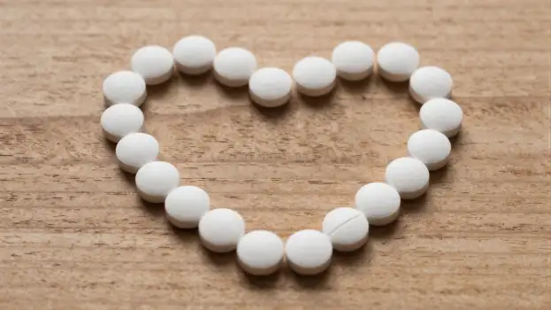 Heart-shapedwhite pills beads on a surface