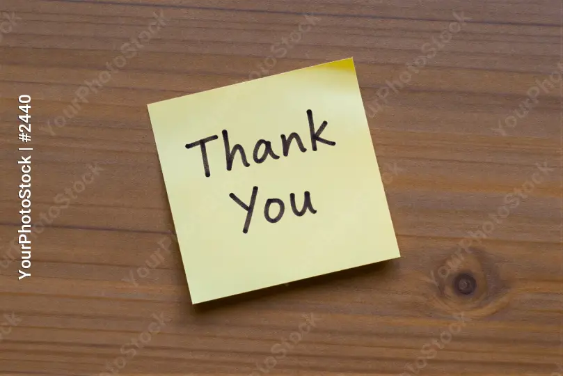 Close-up of 'Thank You' sticky note on wood wooden surface