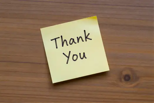 Close-up of 'Thank You' sticky note on wood wooden surface