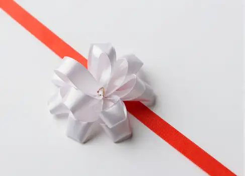 Close-up of a red ribbon tied around a white paper gift box