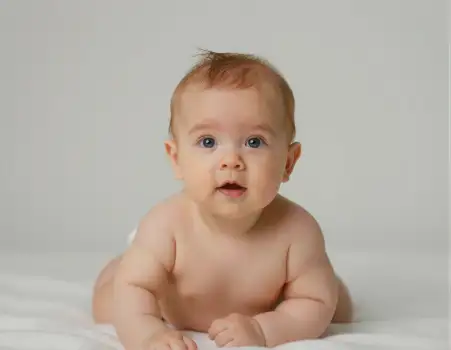 Baby lying on stomach with curious expression