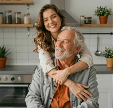 elderly man and young woman smiling in kitchen