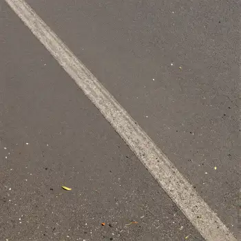 Curved white line on asphalt road with debris