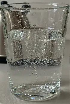 Glass of Water Filled to Brim with Bubbles on Kitchen Countertop