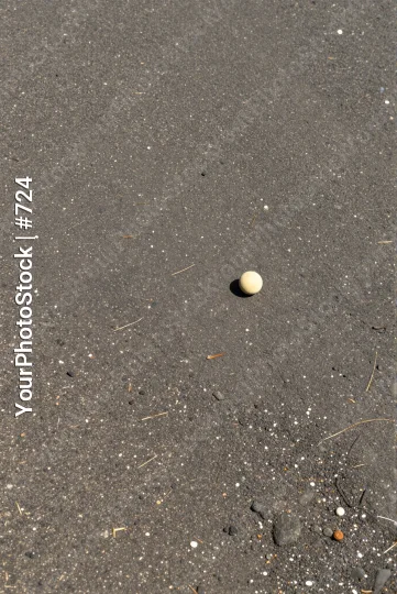 Small white ball on gray asphalt round uneven