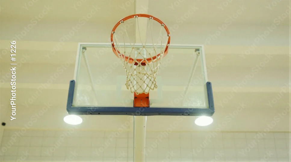 Metal basketball hoop hanging from gym ceiling