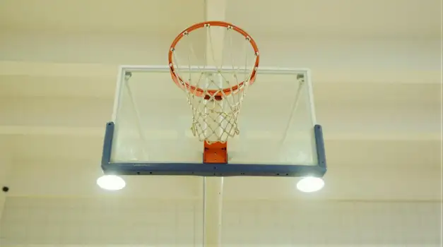 Metal basketball hoop hanging from gym ceiling