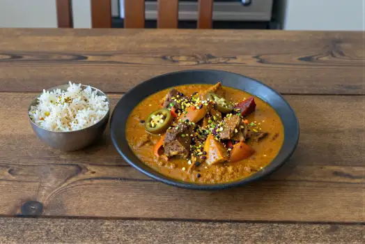 Black Plate with Rice and Curry on Wooden Table