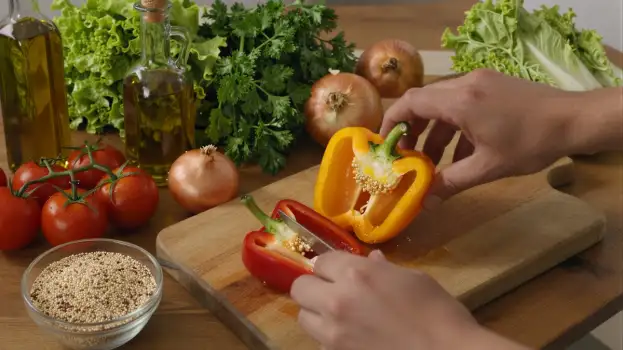 Person Peeling Red Bell Pepper on Cutting Board