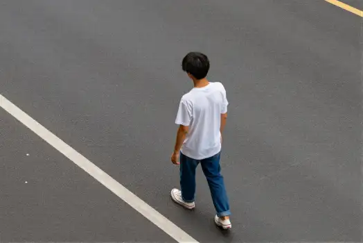 Young Boy Walking on Empty Parking Lot high angle