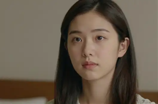Serious Asian Woman in Blurred Bedroom Looking Directly at Camera