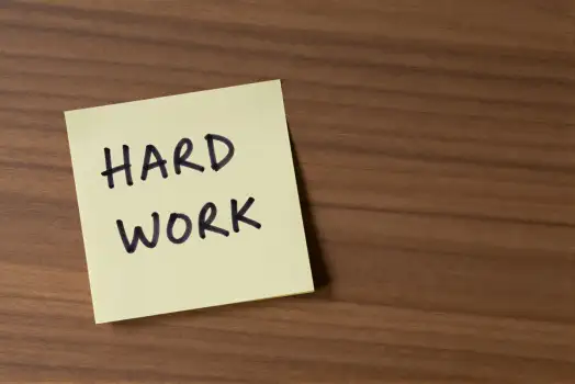 Close-up of 'HARD WORK' sticky note on wood motivation