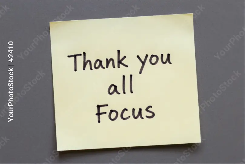 Yellow sticky note with 'Thank You All Focus' on gray surface