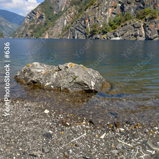 Rocky Lake Shore with Trash and Mountains pebbles