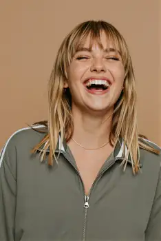 Young Woman Laughing Portrait blonde hair green jacket